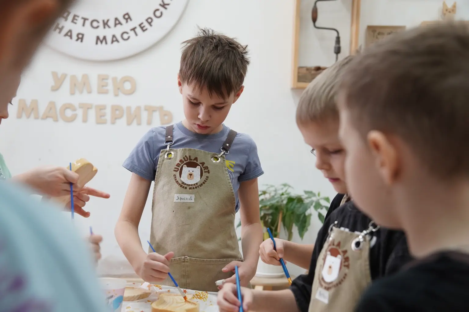 Школьники покрывают деревянное изделие маслом